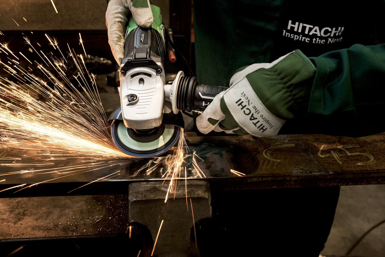 services-01 Close-up of a skilled worker using a grinder with sparks flying in a metal workshop.