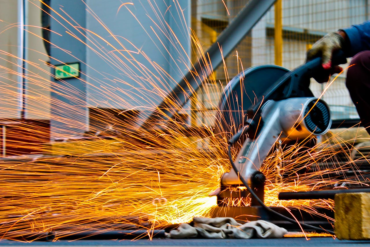 about-01 A worker operates a grinder cutting metal, creating a vibrant display of sparks in an industrial setting.