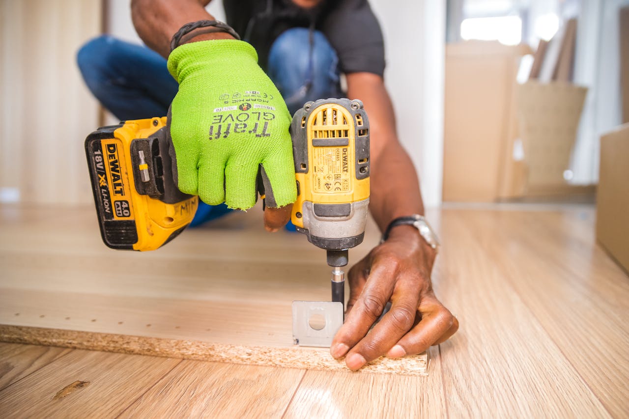 our-services-2 Man using a power drill for home improvement on a wooden floor with precision.