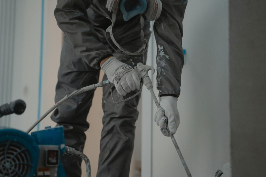 pexels photo 6474193 6474193 Worker in protective gear using a power spray for indoor renovation.